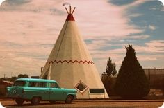 an old car is parked in front of a teepeel shaped building that looks like it's from the 1950's