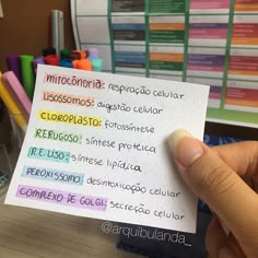 a person holding up a piece of paper with spanish writing on it in front of a pile of school supplies