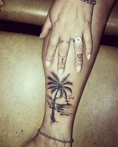 a woman's foot with a palm tree and cross tattoo on her left ankle