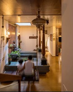 two people are sitting on the floor in front of a water fountain and some statues