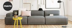 a living room with a gray couch and yellow table in front of the couch is an art piece