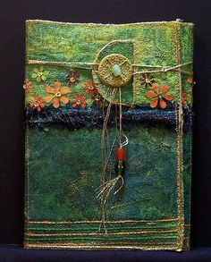 an altered book with flowers and beads on the cover is sitting on a black surface