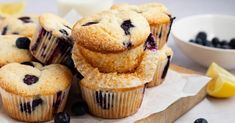 blueberry muffins are piled on top of each other with lemon wedges