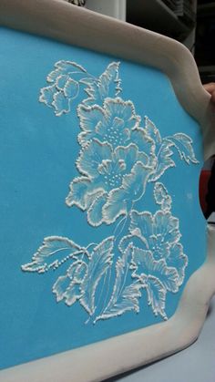 a blue and white tray with flowers drawn on the side is being held up by someone's hand