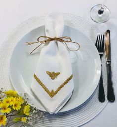 a white plate topped with a napkin and fork next to a vase filled with yellow flowers