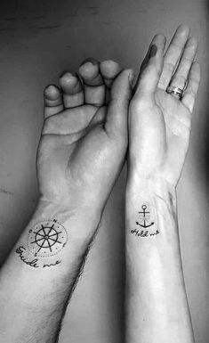 two people with tattoos on their arms holding hands and one has a compass tattoo on the wrist