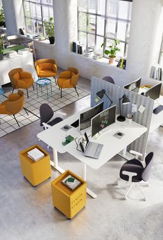 an office with multiple desks and chairs in the center, including two computer screens