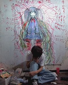 a person sitting on the ground in front of a painting