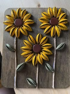 some yellow flowers are sitting on top of a wooden board with white sticks and brown centers