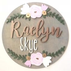 a wooden sign that says raelynn skye with flowers on the front and side