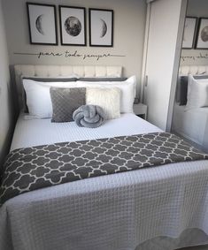 a bed with white sheets and gray pillows