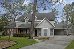 a house with red shutters and trees in the front yard