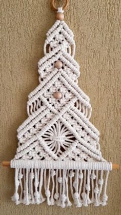 a crocheted christmas tree hanging on the wall with a wooden beaded decoration