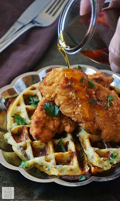 chicken and waffles are being drizzled with syrup on a plate