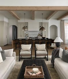 a living room filled with white couches and chairs next to an open kitchen area