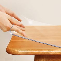 a person using a knife to cut through a piece of paper on top of a wooden table