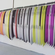 many surfboards are lined up on the wall next to each other in different colors