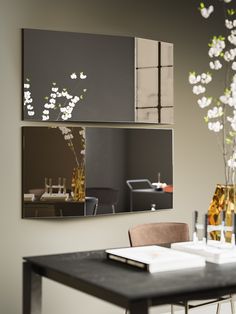 a dining room table with two vases on it and a mirror hanging above it