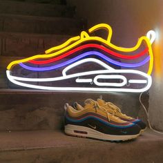 a pair of sneakers sitting on the steps next to a neon sign