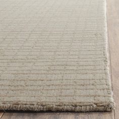 a beige rug is on the floor with wooden floors and wood planks in the background