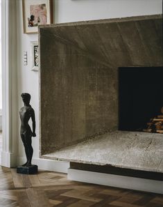 a statue stands next to a fireplace in a room with wooden floors and walls,