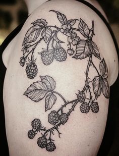 a woman's shoulder with blackberries and leaves tattoo on her left upper arm