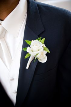 a close up of a person wearing a suit and tie with flowers in his lapel