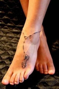 a woman's foot with a tattoo on it and a chain attached to the ankle