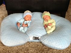 two baby babies laying on top of pillows