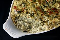 a casserole dish with spinach and cheese in it on a black background