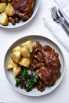 two plates with meat, potatoes and greens on them