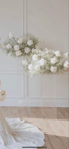 a woman in a wedding dress standing next to a bouquet of white roses and flowers