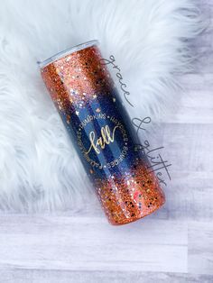 a blue and orange glitter tumbler sitting on top of a white fur covered floor