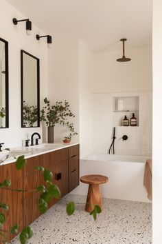 a bathroom with two sinks, mirrors and a bathtub