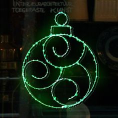 a lighted christmas ornament hanging from the side of a window