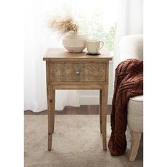 a wooden table with a vase on top of it and a blanket next to it