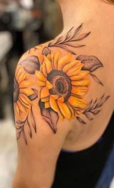 a woman's shoulder with a sunflower tattoo on it