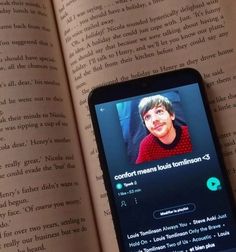 an open book with a cell phone on it's side next to a photo of a child