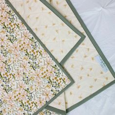 three quilted placemats with flowers on them sitting on a white tablecloth