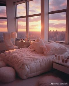 a bed with fluffy blankets and pillows is in front of large windows overlooking the city