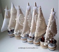 small christmas trees are lined up on the table with white lace and pearls around them