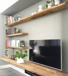 a flat screen tv sitting on top of a wooden shelf next to a book shelf