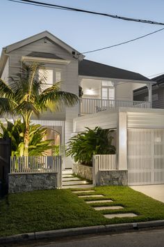 a white house with palm trees in the front yard and stairs leading up to it