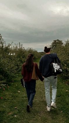 a man and woman walking down a path in an apple orchard with the sky above them