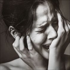 a black and white photo of a woman holding her hands to her face, smiling