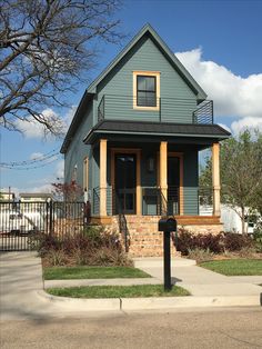 a blue house with brown trim on the front and side windows, is next to a black mailbox