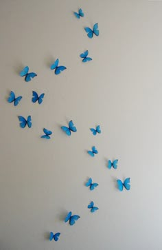 blue butterflies flying in the air on a white wall