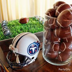 a football helmet is sitting on a table next to other sports memorabilia and balls in a glass jar