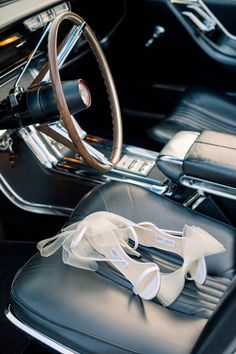 two pairs of white shoes sitting on the dashboard of a black car with a steering wheel