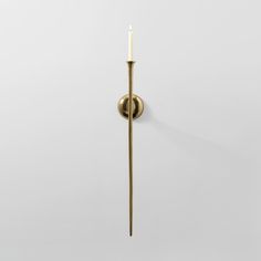 a wall mounted candle holder with a single lit candle in the middle and a white background